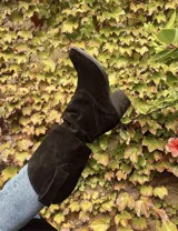 Bota bucanera alta de gamuza negra, con caña arrugada y taco bajo y ancho.