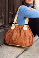 Cartera de cuero color marrón con efecto desgastado, doble asa corta y detalles de remaches.