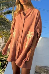 Túnica color salmón de algodón bambula con cuello camisero, mangas 3/4 y bordado de palmeras doradas en el frente.