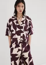 Pantalón largo de corte recto y tiro alto, con estampado abstracto en tonos bordó y crudo. Cuenta con cintura ajustable con elástico y un lazo incorporado para anudar.