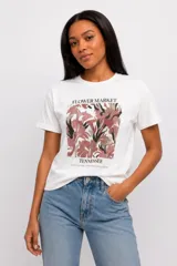 Remera de manga corta blanca, al cuerpo y con cuello redondo. Presenta un estampado frontal con diseño floral y la inscripción "Flower Market Tennessee".