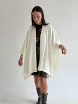 Ruana de tejido de punto trenzado en color crudo, con diseño abierto, corte holgado y mangas amplias tipo kimono.
