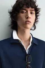 Jersey de punto color azul marino, de corte relajado, con cuello solapa y cierre frontal de tres botones. Presenta mangas largas y acabados en rib en puños y bajo.