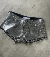 Short de tiro bajo confeccionado en tela cubierta de lentejuelas plateadas, con diseño de cinco bolsillos y ruedo deshilachado.