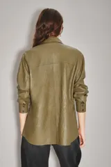 Camisa de cuero ovino color verde oliva, con cuello clásico, cierre frontal con botones y mangas largas con puños abotonados. Presenta un corte holgado y diseño tipo sobrecamisa.