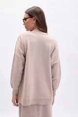 Buzo de tejido de punto color beige con hilo de lurex que le da un brillo sutil. Presenta cuello redondo, mangas largas y un calce holgado.