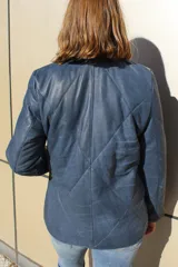 Campera de cuero azul con acabado gastado, diseño acolchado con costuras en forma de rombos, cierre frontal completo y bolsillos laterales.
