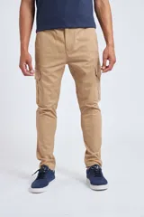 Pantalón cargo color beige de corte slim, con cierre y botón frontal, bolsillos laterales tipo cargo y diseño sin puños en los tobillos.