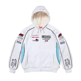 Campera con capucha Supreme estilo racing de color gris melange, con interior de corderito blanco, cierre frontal completo y bolsillos tipo canguro. Presenta múltiples parches y estampados de estilo automovilístico en el pecho y las mangas, además de detalles en color celeste y ribetes negros.