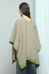 Poncho marrón con detalles de bordes ondulados en color rosado, confeccionado en mezcla de acrílico, poliéster y elastano, de diseño abierto y mangas amplias.