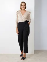 Enterito combinado de fiesta marca Julia Jordan. El torso es de lentejuelas color beige con escote en V cruzado y mangas largas abullonadas. La cintura es elastizada con lazo de ajuste y el pantalón es negro con bolsillos verticales. La espalda tiene cierre invisible y el torso está forrado.