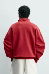 Sudadera de corte relajado color rojo con efecto lavado. Presenta cuello subido con cierre frontal de botones a presión, manga larga y puños y ruedo terminados en rib.