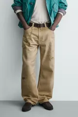 Pantalón straight fit de algodón con efecto lavado y roturas localizadas. Presenta diseño de cinco bolsillos, cierre frontal con cremallera y botón metálico.