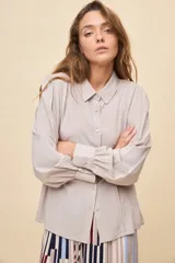 Camisa de manga larga color celeste, con cuello clásico y botonadura frontal. Presenta un calce relajado, con mangas amplias y puños anchos.