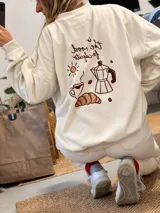 Buzo oversize color beige, con cuello redondo y diseño estampado en la espalda de temática cafetera con cafetera moka, taza, medialuna y sol.