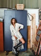 Blazer de cuero color celeste metalizado, con solapas, cierre con broches tipo tanca de madera y puños con detalle de piel sintética marrón.