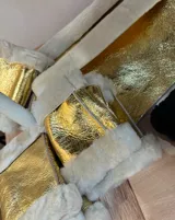 Conjunto de mitones y cuello de cuero sintético dorado con borde de piel sintética blanca.