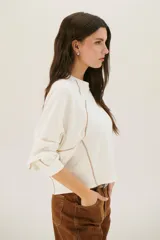 Buzo negro de corte cropped con mangas largas abullonadas y costuras a la vista en color blanco.