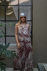 Mono largo de mujer, color verde oscuro, con estampado de hojas de palmera en blanco. Diseño de tirantes finos y escote redondo, con ajuste en el busto mediante un accesorio tipo broche o hebilla dorada.