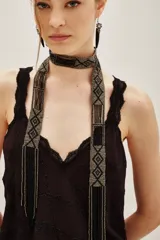 Collar largo tipo bufanda de cuentas de vidrio, con diseño geométrico en tonos negro y plateado, terminado en flecos.