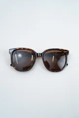 Lentes de sol con armazón de carey en tonos marrones y negros, con cristales oscuros.