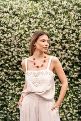 Conjunto color crudo compuesto por un top calado y bordado, y un pantalón de pierna ancha pinzado con bolsillos.