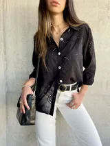 Camisa negra con bordado calado, corte recto y aberturas laterales.