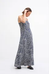 Maxi vestido de tirantes finos con estampado abstracto de líneas onduladas en tonos azul, negro y crema. Presenta un corte fluido y holgado con un ligero vuelo en el ruedo.
