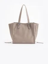 Bolso tipo tote de cuero color tostado con doble asa de hombro, detalles de hebillas metálicas en el frente y cierres laterales decorativos.