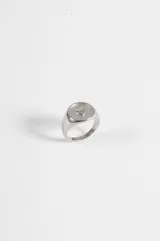 Anillo de acero quirúrgico tipo sello, color plateado, con detalle de relieve en forma de corazón en la parte superior.