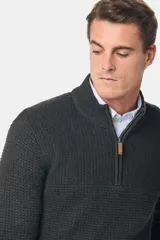 Buzo tejido de punto con textura, cuello alto y cierre frontal parcial. Presenta puños y ruedo acanalados, con un diseño clásico y versátil.