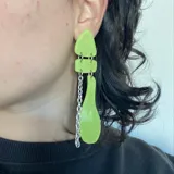 Aros colgantes con piezas geométricas de color verde lima unidas por argollas metálicas y cadenas plateadas.