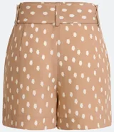 Short color beige con estampado de lunares blancos, tiro medio, trabillas en la cintura y cinturón forrado con hebilla.