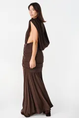 Vestido largo color chocolate, con escote profundo drapeado y falda con frunces laterales que aportan movimiento.