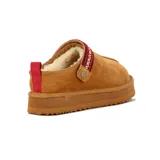 Zuecos de gamuza color tostado con plataforma dentada, forro interior sintético tipo corderito y tira superior decorativa con bordado étnico en tonos rojos y beige.