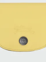 Tarjetero de cuero color amarillo, modelo Le Pliage Xtra de Longchamp, con diseño plegable y cierre de botón a presión.