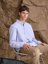 Camisa de corte clásico confeccionada en tejido Oxford de algodón, con cuello camisero, cierre frontal de botones y bolsillo en el pecho.