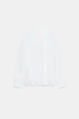 Camisa blanca de manga larga con cuello tipo pañuelo drapeado y bordados perforados (broderie) en la parte inferior y puños.