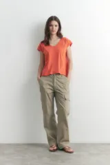 Remera naranja de corte recto, con cuello en V y mangas cortas. Presenta detalle de vainillas en los laterales y en los hombros.