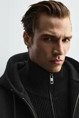 Sudadera con capucha de corte relajado confeccionada en tejido técnico con elasticidad y acabado efecto neopreno. Presenta cierre frontal de cremallera de doble dirección, bolsillos tipo canguro y terminaciones en rib.