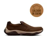 Zapato casual tipo slip-on de cuero marrón con textura granulada. Presenta paneles elásticos laterales para un ajuste cómodo, suela de goma con diseño de tracción y entresuela en tono beige.