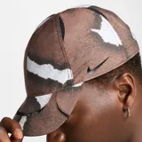 Gorro de visera Nike Nocta color marrón con estampado abstracto en tonos marrones y blancos. Logotipo de Nocta bordado en el lateral.