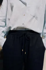 Pantalón azul marino de lino, de tiro alto con cintura elástica ajustable con cordones, bolsillos delanteros y pernera recta.