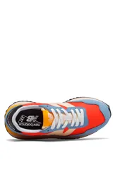 Championes New Balance WS237 con diseño inspirado en el running retro, confeccionados con base de tejido rojo, revestimientos de gamuza celeste y detalles en beige, negro y amarillo.