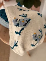 Chaleco de punto color blanco con diseño de perritos bordados en tonos azules, grises y amarillos, con cuello redondo y amplia sisa.