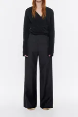 Pantalón largo negro de denim, corte amplio, con cierre frontal con corchete oculto y cremallera, y bolsillos laterales. Contiene 20% de fibras recicladas.