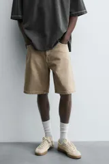 Bermuda de denim de algodón, color verde claro lavado, de corte recto y tiro medio. Presenta cinco bolsillos y cierre frontal con cremallera y botón.