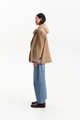 Tapado corto tipo blazer confeccionado en lana de color tostado. Presenta una capucha integrada, cierre frontal con dos botones negros y bolsillos laterales con solapa.