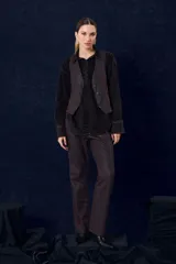 Chaleco de denim con proceso de encuerado, de corte recto y escote en V. Presenta cierre frontal con botones y bolsillos delanteros con solapa.