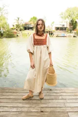 Túnica de lino color crudo con corte holgado y mangas abullonadas con elástico. Presenta una pechera frontal y trasera con estampado étnico en tonos terracota y amarillo.